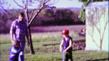 1968: Dad pitching baseball to sons practicing backyard fun.