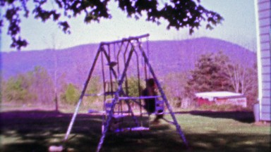1968: Boy swing set in country rural mountainous setting.