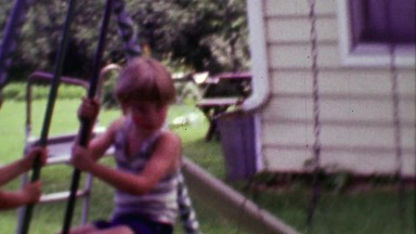 1968: Kids swinging on seesaw style playground lifting up from ground.