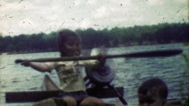 1953: Young girl showing she can paddle family canoe across lake.