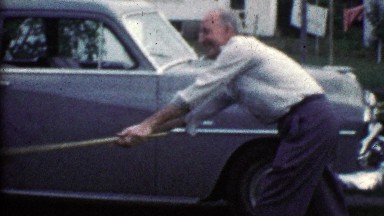 1953: Grandpa playfully spanks kid with broom while grandma helps.