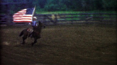 1955: USA flag proudly flown by a horse riding cowboy for rodeo.