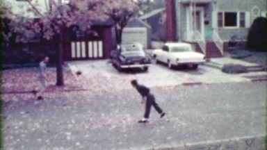 1963: Son and father toss pigskin football around residential roads.