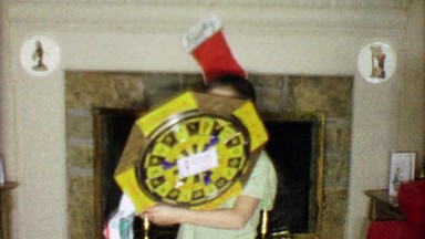 1963: Boy gets dartboard for Christmas gift in front of holiday fireplace.
