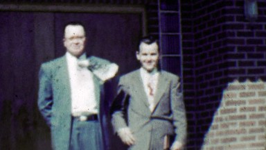 1951: Businessmen wind blows necktie dressed in expensive suits.