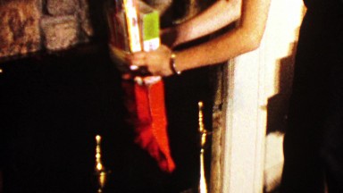 1964: Boy dumps overfilled Christmas stocking on ottoman chair.