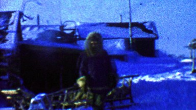 1957: Native man leaving winter trappers house fur coat.