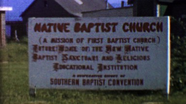 1957: Native Baptist Church sign grand opening founders waving.