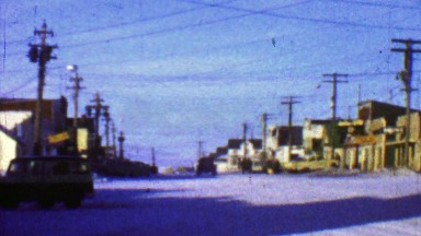 1957: Downtown business district man walking fast in cold winter weather.