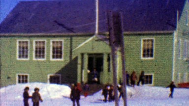 1957: One room schoolhouse kids play outside winter cold sunny day.