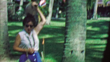 1964: Drunk mature woman puts big coconut on head drops in on ground.