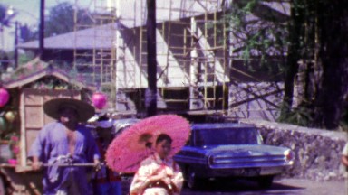 1964: Japanese style parade man pulling traditional merchant cart.