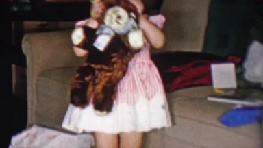 1956: Cute toddler girl hiding behind stuffed animal plush bear toy.