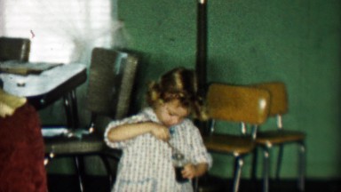 1957: Young Girl Blowing Soap Bubbles Indoors in Kitchen