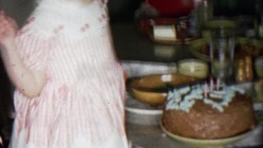 1956: Toddler Girl Blowing Out Birthday Cake Candles as Proud Parents Watch