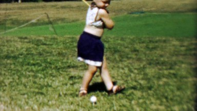 1956: Toddler girl golf attempt chasing ball with cutdown short club.