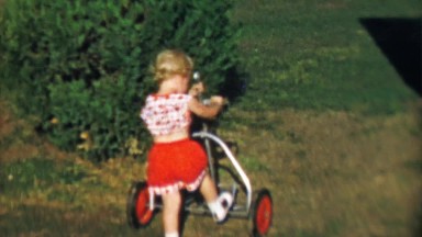 1956: Toddler girl exploring empty pull style golf cart.