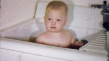 1953: Baby splashing in kitchen sink makeshift bathtub.