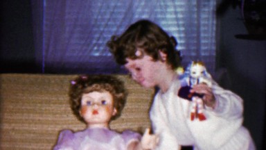 1958: Young Girl Struggles to Lift Giant Plastic Toy Doll