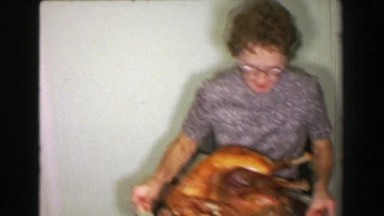 1957: Mother bringing out Thanksgiving turkey dinner father carving bird.