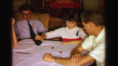 1957: Family playing dice rolling craps gambling game at den table. DAVENPORT,