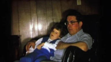 1957: Boy Waking Up in Dad's Lap Confused in Davenport, Iowa
