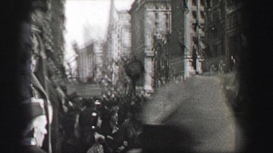 1937: downtown city crowd watching parade from sidelines.