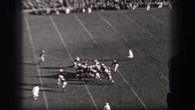 1937: Harvard University football game running play man stands up in fedora hat.