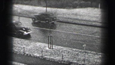 1937: Harvard University buildings snowy day car traffic on North Bridge.