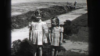 1939: Young girls in formal dress with wavy curly long bangs hair style.