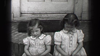 1939: Young girls sitting front porch stoop with wavy curly long bangs hair