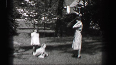1939: Mother calling young girls in white formal sundress to come inside for