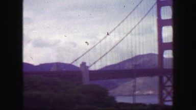 1939: Golden gate bridge pan Fort Point fedora hat man parked classic cars. SAN