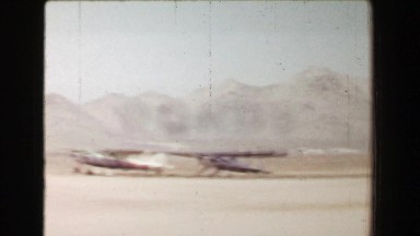 1968: Hazy mountainous desert airfield small propeller airplanes waiting on