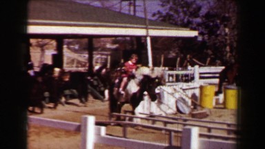 1957: Young Girl Riding Horse at Farm Petting Zoo Near White Picket Fence Stables