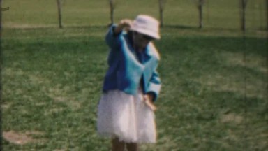 1962: Young girl playing yo-yo toy in Easter spring white hat and dress skirt.