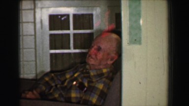 1958: Grandpa tired after big dinner resting feet up on ottoman style chair. ST.