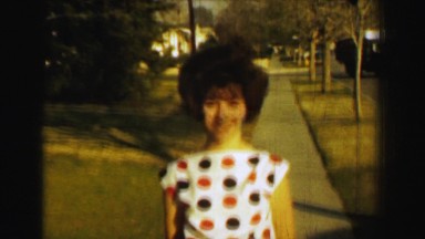 1958: Teenage girl curly perm hair polka dot blouse small orange shorts. ST.