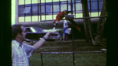 1977: Man Feeding Pet Red Parrot Crackers in Fashionable Bright Yellow Pants