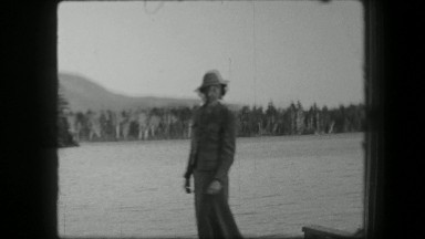 1938: Women formally dressed at lakeside dock waters waving to camera. SARATOGA
