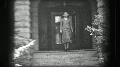 1938: Woman leaving wealthy mansion style stone brick home staircase. SARATOGA