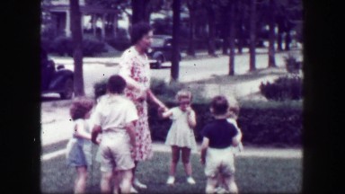 1949: Schoolmarm teacher playing kids front yard holding hands. MACON, GEORGIA