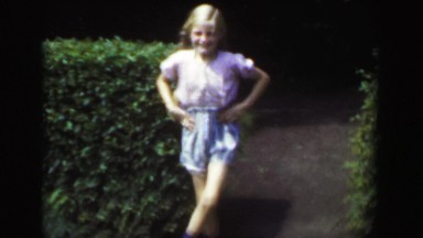 1949: Blond long braided hair light skinned girl dancing jig outdoor shorts.
