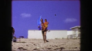 1955: Fit sunglasses dad carries son beach vacation holiday white sands.