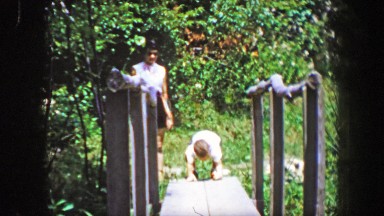 1956: Brave son showing mother crossing narrow path bridge.
