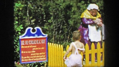 1955: Storyland theme park old women in a shoe house building boy waving window.