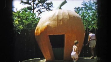 1955: Storyland Theme Park Mother and Boy Circling Giant Pumpkin House