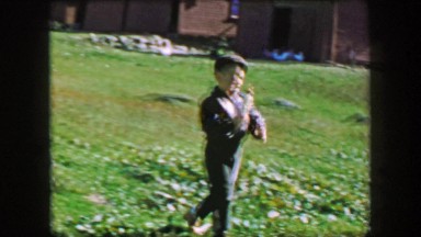 1957: Boy proudly hand feeding sheep bottle of milk at country farm.