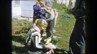 1957: Family harvesting corn ears peeling protective shell away from ears.
