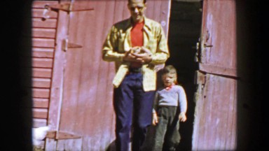 1957: Family leaving barn petting tiny kitten at family farm.